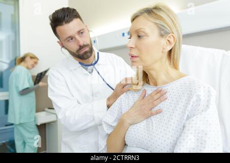 doctor using stethoscope to examine anxious woman Stock Photo