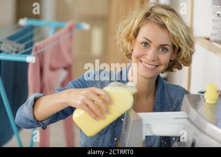 woman pouring fabric conditioner into washing machine drawer Stock Photo