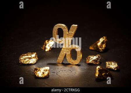 Gold percent sign and gold nuggets on black background. Stock Photo