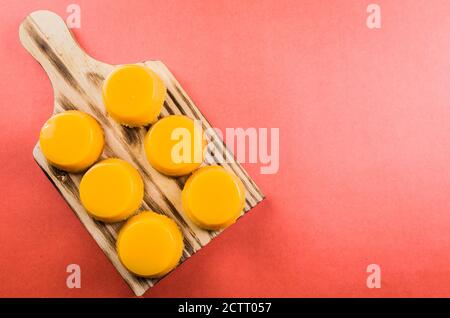Delicious Quindins on wooden board, traditional Brazilian dessert made with egg yolk, sugar and coconut. Stock Photo