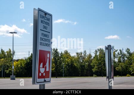 A bilingual sign in an Ottawa, Ontario parking lot marks a parking space as reserved for expectant mothers only in both English and French languages. Stock Photo