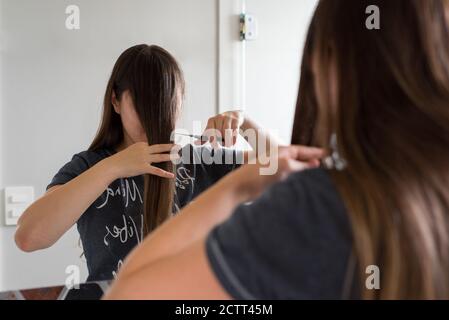 Young woman in home bathroom cutting her own hair with scissors Stock Photo  - Alamy