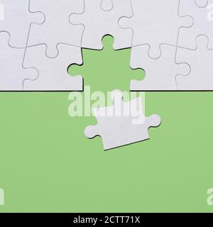 Last puzzle piece in jigsaw puzzle on green background Stock Photo