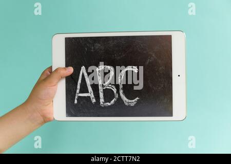 Hand of child (6-7) holding digital tablet showing alphabet Stock Photo