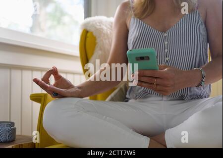 Midsection of woman using smartphone and practicing yoga Stock Photo