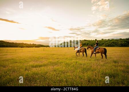 USA, Utah, Salem, Sisters (14-15) riding horses at sunset Stock Photo
