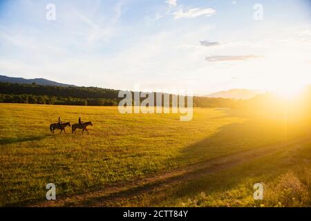 USA, Utah, Salem, Sisters (14-15) riding horses at sunset Stock Photo
