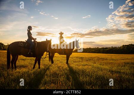 USA, Utah, Salem, Father and daughter (14-15) riding horses at sunset Stock Photo