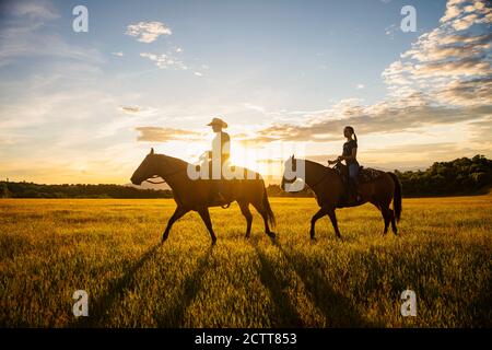 USA, Utah, Salem, Father and daughter (14-15) riding horses at sunset Stock Photo