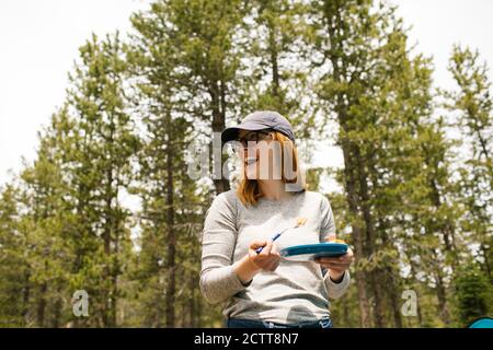 Smiling woman holding plate on camping in forest, Wasatch-Cache National Forest Stock Photo