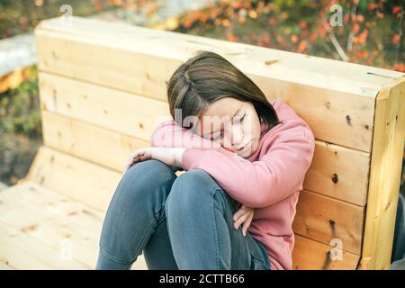 Portrait of sad and bored girl 7-8 years old in a city park Stock Photo