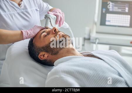 Doctor beautician treating male skin with laser device Stock Photo