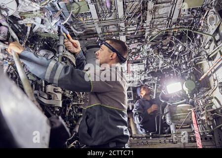 Engineers working with aircraft in repair hangar Stock Photo