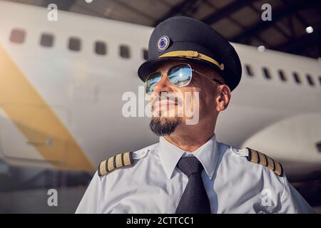 Bearded handsome man in pilots hat looking at the sunny sky Stock Photo