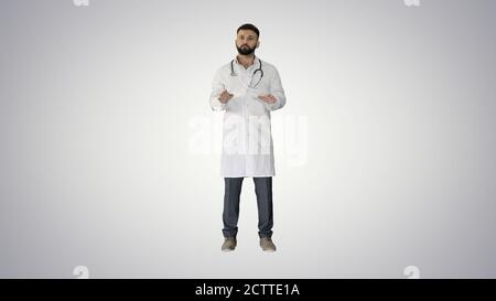 Confident doctor talking and looking into the camera on gradient Stock Photo