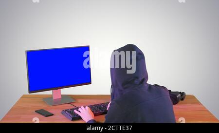 Hacker in hood cracking code using pc on gradient background. Stock Photo