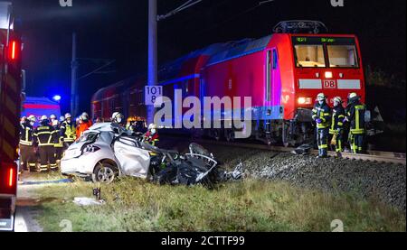 24 September 2020, Lower Saxony, Uelzen: Emergency fire brigade units stand next to a car wreck and a regional train near a level crossing near Uelzen. A car driver was hit by the regional train with her car at the level crossing and died still in the vehicle. She was dragged along for several hundred meters. The woman had driven her car past the closed half-barriers of the crossing on Thursday evening. The vehicle was rammed by the railway and completely destroyed. The train driver suffered a shock. Because of the rescue work, rail traffic on the line was initially suspended. Photo: Philipp S Stock Photo