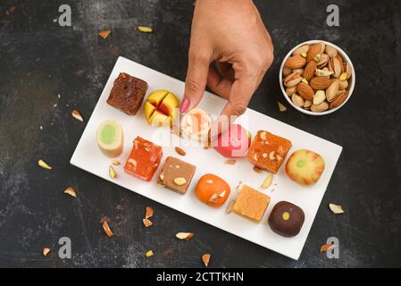 Indian sweets, mithai milk Peda and Halwa or Halva, woman holding Diwali sweets in hand flavored variety assorted dessert Deepavali, Pongal, Dussehra Stock Photo