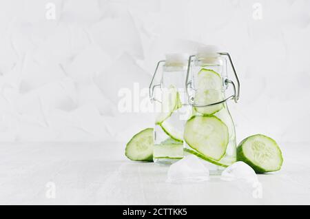 Cold fresh detox beverages of green cucumber with soda water, bubbles, ice cubes on simple soft bright white background, copy space. Stock Photo