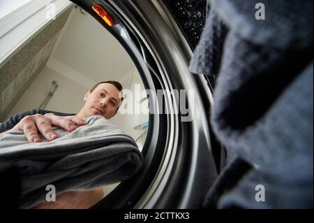 Young man using washing machine view from inside Stock Photo
