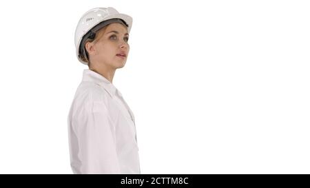 Young woman in hard hat walking and looking around on white back Stock Photo