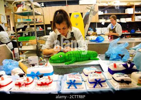 OXFORD, UK - AUGUST 23, 2017:  Woman making Crocodile cake decoration in Cake Shop bakery at historic Oxford Covered Market. Stock Photo