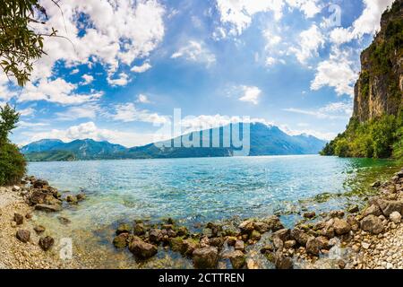 Nature wilderness landscape at lake Garda, Italy on a beautiful summer day. Blue water, rocks, mountains, sunlight and clear sky. Stock Photo