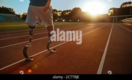 Athletic Disabled Fit Man with Prosthetic Running Blades is Walking During a Training on an Outdoor Stadium on a Sunny Afternoon. Amputee Runner Stock Photo
