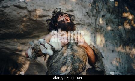 Portrait of Primeval Caveman Wearing Animal Skin Looks Around Forest Defending His Cave and Territory in the Prehistoric Times. Prehistoric Stock Photo