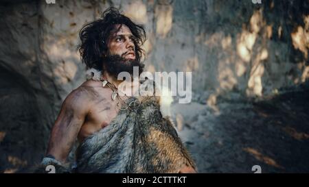 Portrait of Primeval Caveman Wearing Animal Skin Looks Around Forest Defending His Cave and Territory in the Prehistoric Times. Prehistoric Stock Photo
