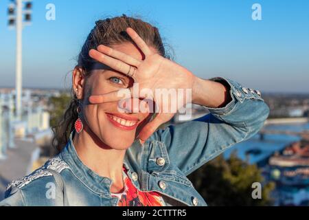 Funny young woman covering her face with hand in sunshine, outdoors Stock Photo