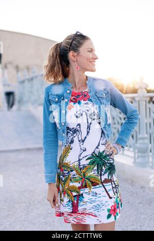 Happy young stylish urban woman posing outdoors in sunset Stock Photo