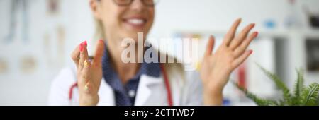 Woman doctor in glasses smiles and holds pen in her hands Stock Photo