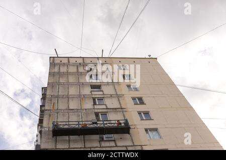Renovation of the facade of an old building. Workers in a suspended construction cradle Stock Photo