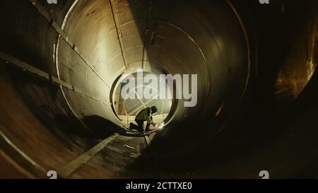 Professional Heavy Industry Worker Wearing Helmet Welding Inside Oil and Gas Pipe. Construction of the Oil, Natural Gas and Biofuels Transport Stock Photo
