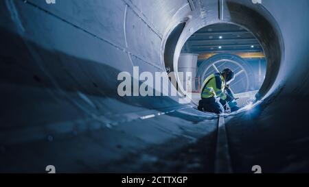 Professional Heavy Industry Welder Working Inside Pipe, Wears Helmet and Starts Welding. Construction of the Oil, Natural Gas and Fuels Transport Stock Photo