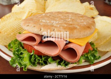 A bologna sandwich on thin round sandwich bread with potato chips Stock Photo