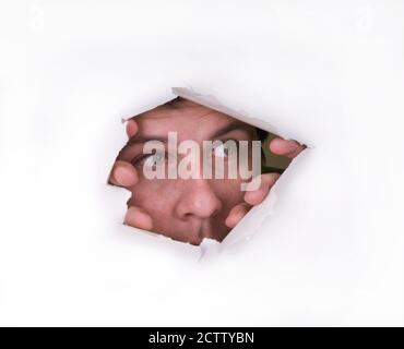 A man looks through a hole in the paper Stock Photo