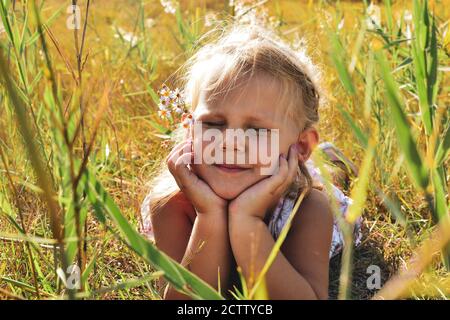 Portrait of a cute and beautiful baby. The child lies in the grass. Summer childhood moments in nature Stock Photo