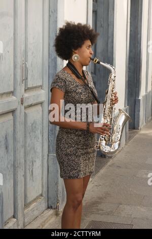 Young woman musician playing saxophone in shopping street, Santa Cruz, La Palma, Canary Islands Stock Photo