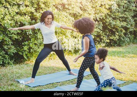 Black African American mom with child playing yoga family activity together at backyard during self quarantine at home. Stock Photo