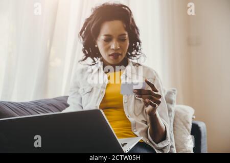 African or Black people hand and looking at name card or credit card with laptop computer search at home or online shopping concept. Stock Photo