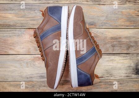 Men's sports brown shoes with blue inserts on a wooden background, view top Stock Photo