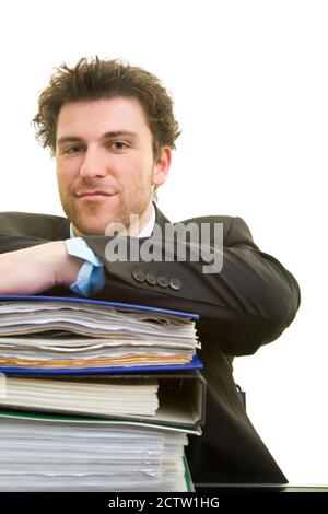 Young man in a suit at his desk with a pile of files Stock Photo