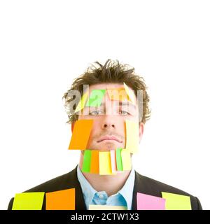 Young man in suit with lots of sticky notes on his face and body Stock Photo