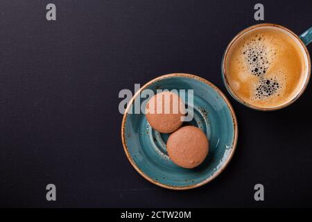 Blue cup of coffee and macaroons on the dark wooden table. Coffe break. Top view. Flat lay Stock Photo