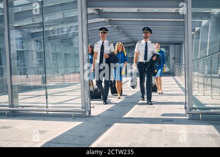 Aircrew with travel suitcases walking in airport terminal Stock Photo