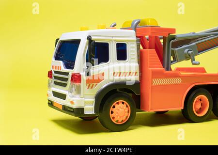 Toy orange tow truck on yellow background banner with space for text. Children's car for loading and transporting cars Stock Photo