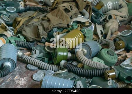 A lot of old gas masks are lying on the floor in an abandoned building Stock Photo