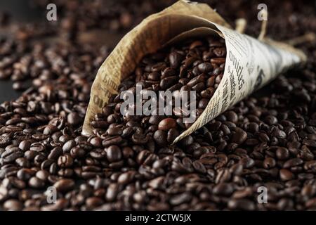 Black coffee beans studio shot. Freshly roasted coffee beans in a cone of paper Stock Photo